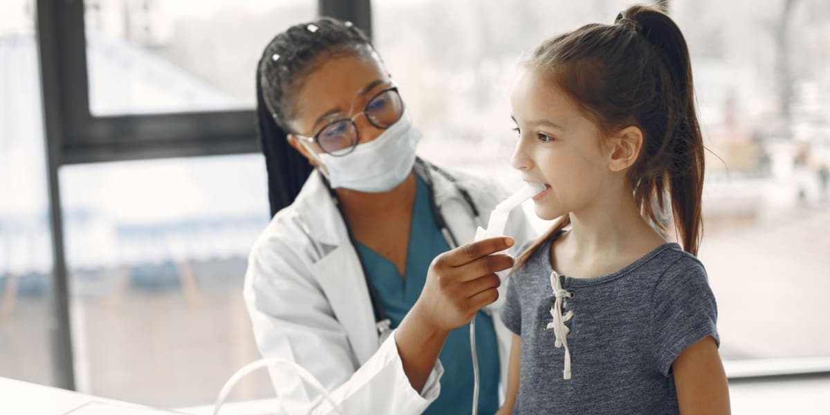 A doctor helps a young girl use a nebuliser at a children’s clinic